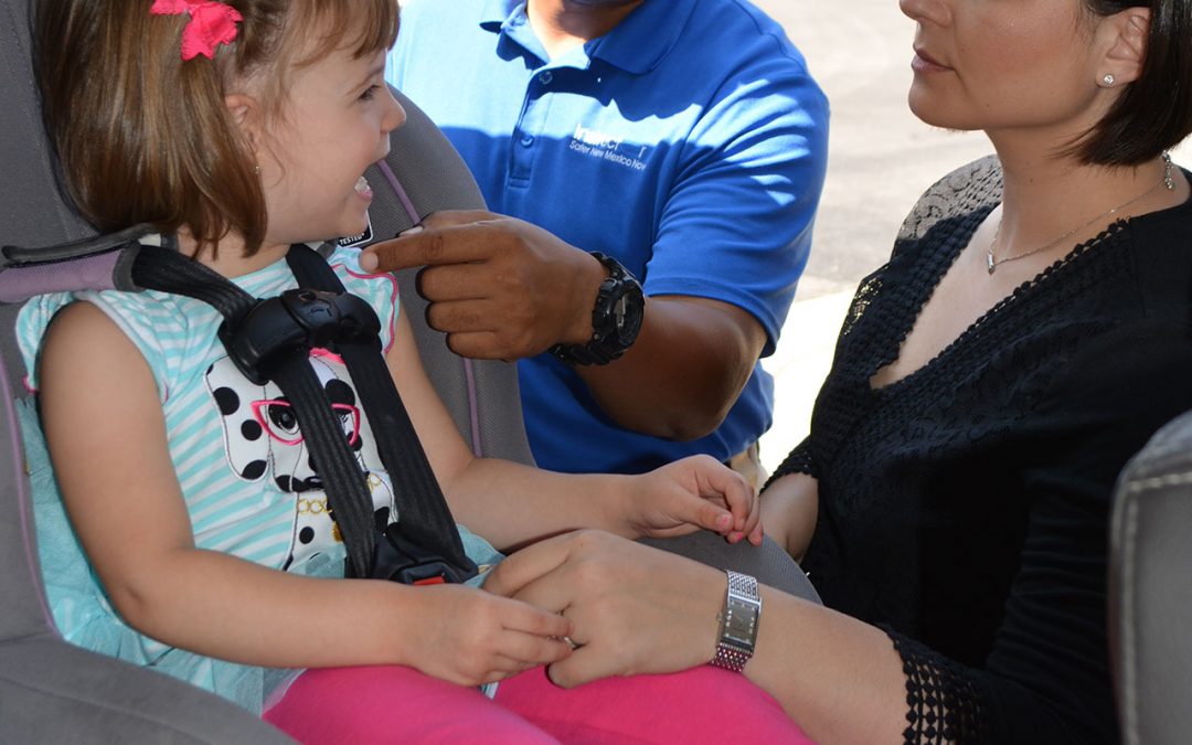 Instructor shows parent how to properly buckle up child in car seat